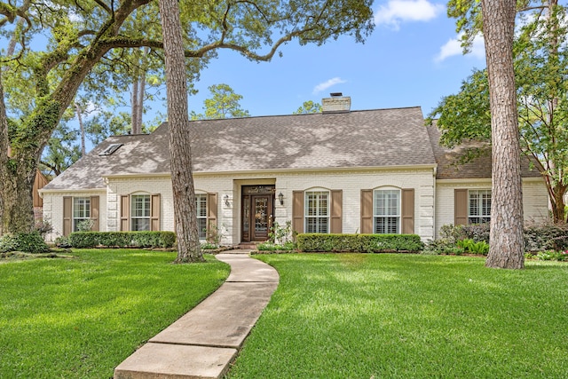 12215 Cobblestone Dr, Houston, TX 77024 - cape cod-style house featuring brick siding, roof with shingles, a front yard, and a chimney