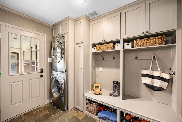 12215 Cobblestone Dr, Houston, TX 77024 - washroom with estacked washer and dryer, stone tile floors, cabinet space, and ornamental molding