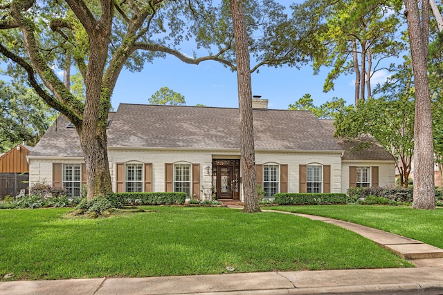 12215 Cobblestone Dr, Houston, TX 77024 - cape cod house with brick siding, a front yard, roof with shingles, and a chimney