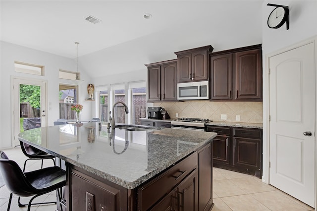 13015 Barkley Bend Ln, Houston, TX 77044 - kitchen with stainless steel microwave, decorative backsplash, a kitchen breakfast bar, stone countertops, and range