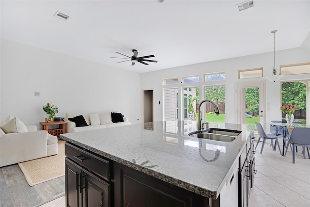 13015 Barkley Bend Ln, Houston, TX 77044 - kitchen featuring open floor plan, ceiling fan, an island with sink, and light stone counters