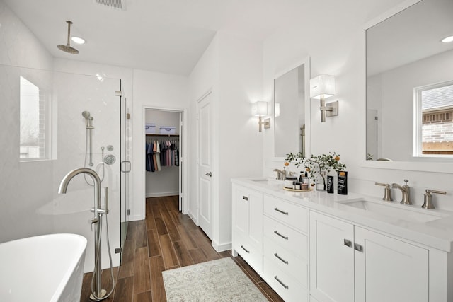21218 Blue Bluff Dr, Cypress, TX 77433 - full bath featuring a stall shower, double vanity, a freestanding tub, wood finished floors, and a spacious closet