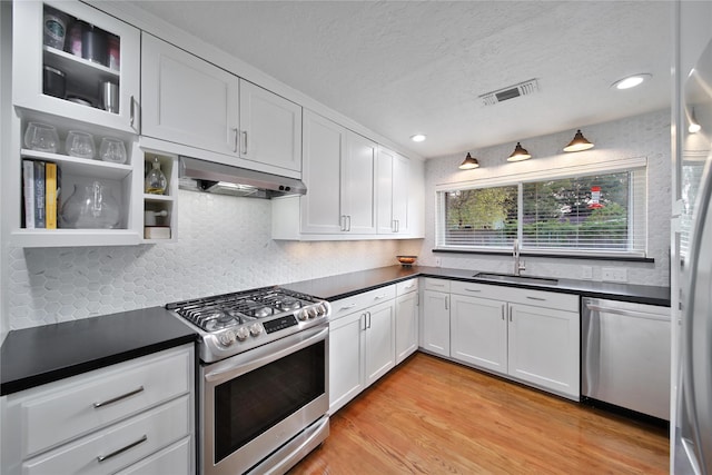 2007 Wakefield Dr, Houston, TX 77018 - kitchen with stainless steel appliances, under cabinet range hood, dark countertops, white cabinetry, and a textured ceiling