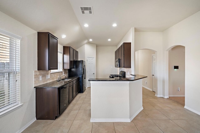 19842 Haven Cliff Ln, Cypress, TX 77433 - kitchen with backsplash, dark brown cabinetry, black appliances, arched walkways, and light tile patterned floors