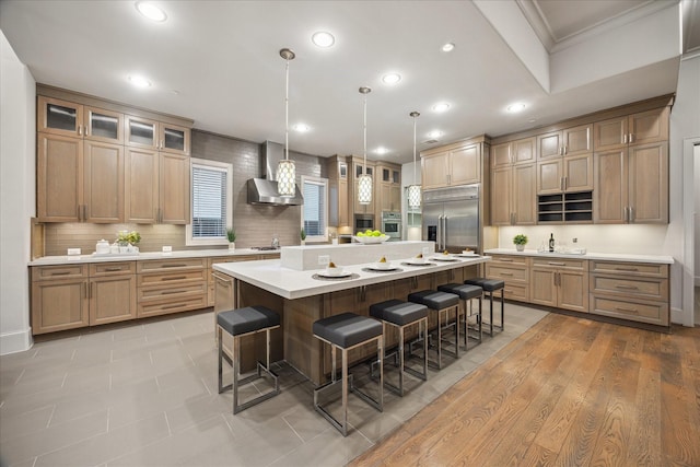 4615 Verone St, Bellaire, TX 77401 - kitchen featuring appliances with stainless steel finishes, wall chimney range hood, a breakfast bar, light countertops, and ornamental molding