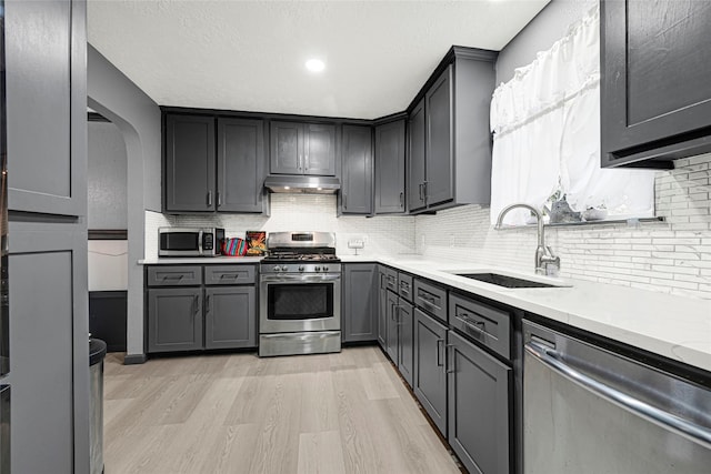17103 Scuttle Way, Crosby, TX 77532 - kitchen featuring appliances with stainless steel finishes, under cabinet range hood, light wood finished floors, light countertops, and tasteful backsplash