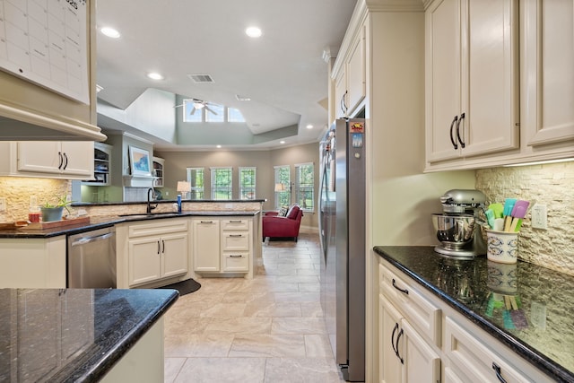 111 Bessie Price Owen Dr, Montgomery, TX 77356 - kitchen with stainless steel appliances, a ceiling fan, decorative backsplash, a peninsula, and dark stone counters