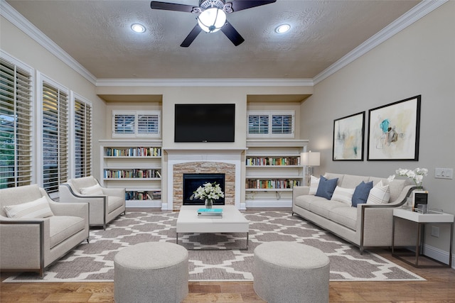 107 Lake View Loop, Fulshear, TX 77441 - living area featuring a textured ceiling, crown molding, ceiling fan, wood finished floors, and a stone fireplace