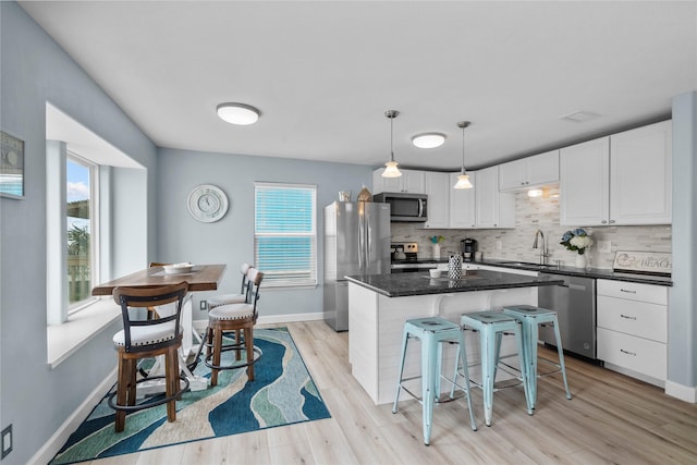 21446 Gulf Dr, Galveston, TX 77554 - kitchen featuring stainless steel appliances, backsplash, white cabinetry, a breakfast bar, and light wood-style flooring