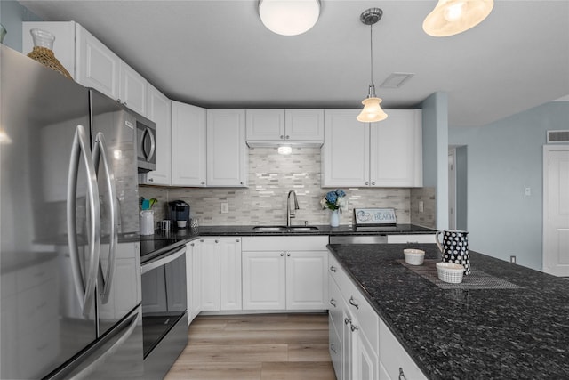 21446 Gulf Dr, Galveston, TX 77554 - kitchen featuring appliances with stainless steel finishes, light wood-style floors, white cabinets, hanging light fixtures, and backsplash
