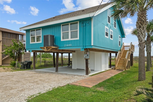 21446 Gulf Dr, Galveston, TX 77554 - back of house featuring stairway, a carport, driveway, a shingled roof, and a yard