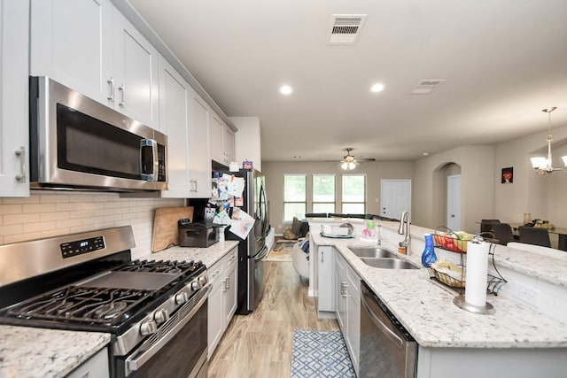 7947 Cinderella St, Houston, TX 77028 - kitchen featuring appliances with stainless steel finishes, a center island with sink, light wood-style floors, a ceiling fan, and a chandelier