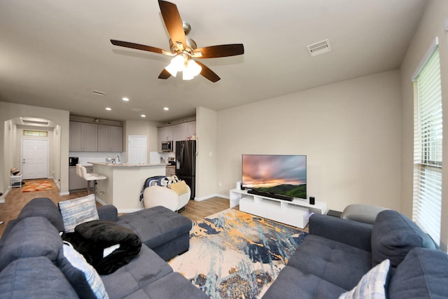 7947 Cinderella St, Houston, TX 77028 - living room with arched walkways, light wood-style floors, ceiling fan, and recessed lighting