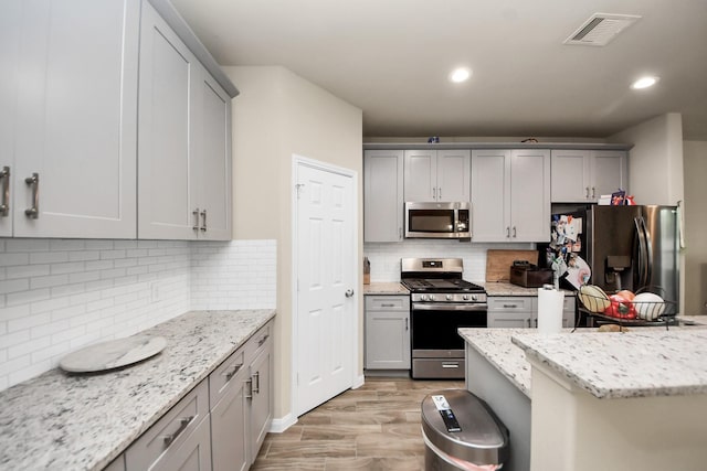 7947 Cinderella St, Houston, TX 77028 - kitchen featuring appliances with stainless steel finishes, gray cabinetry, tasteful backsplash, and recessed lighting
