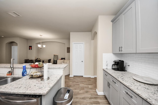 7947 Cinderella St, Houston, TX 77028 - kitchen with dishwasher, tasteful backsplash, arched walkways, light wood-style floors, and hanging light fixtures