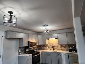 1719 Adina St, Austin, TX 78721 - kitchen with stainless steel appliances, gray cabinetry, light countertops, and tasteful backsplash