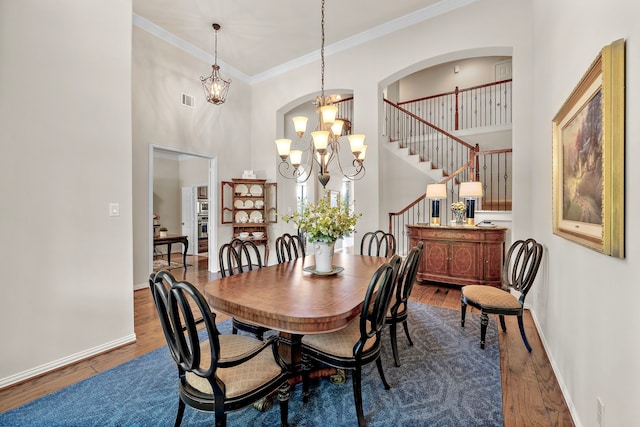 18331 Chapmans Count Rd, Cypress, TX 77433 - dining space with wood finished floors, a chandelier, a high ceiling, crown molding, and stairway