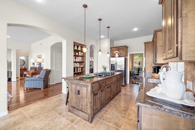 18331 Chapmans Count Rd, Cypress, TX 77433 - kitchen featuring appliances with stainless steel finishes, dark stone countertops, arched walkways, a kitchen island, and a breakfast bar area