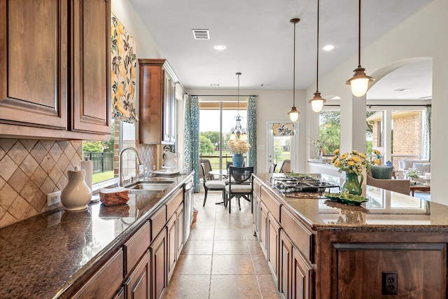 18331 Chapmans Count Rd, Cypress, TX 77433 - kitchen with stainless steel gas cooktop, a center island, backsplash, dark stone countertops, and hanging light fixtures