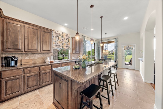 18331 Chapmans Count Rd, Cypress, TX 77433 - kitchen with backsplash, dark stone countertops, a kitchen island, a breakfast bar area, and stainless steel gas cooktop