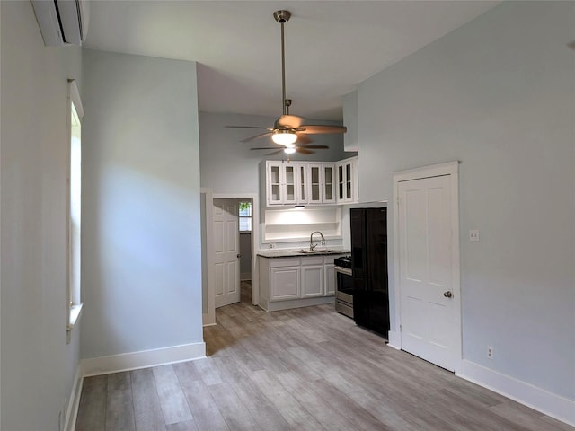 1805 39th St, Galveston, TX 77550 - kitchen with a wall mounted air conditioner, a ceiling fan, white cabinetry, stainless steel range, and light wood-style floors