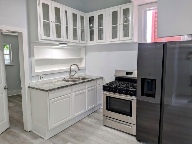 1805 39th St, Galveston, TX 77550 - kitchen featuring appliances with stainless steel finishes, light wood finished floors, white cabinetry, glass insert cabinets, and light stone counters