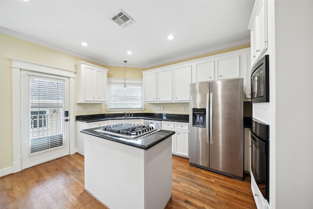 606 E 27th St, Houston, TX 77008 - kitchen featuring black appliances, white cabinetry, dark countertops, a center island, and ornamental molding