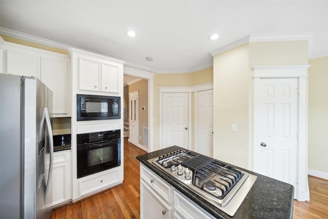606 E 27th St, Houston, TX 77008 - kitchen with black appliances, light wood-style floors, crown molding, white cabinets, and dark stone countertops