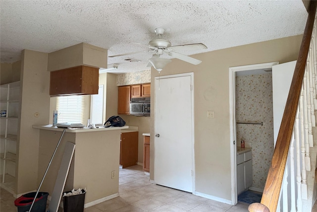 3600 Jeanetta St Unit 1602, Houston, TX 77063 - kitchen featuring stainless steel microwave, ceiling fan, brown cabinets, light tile patterned floors, and a textured ceiling
