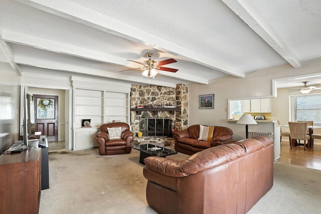 2910 Riata Ln, Houston, TX 77043 - living area with a ceiling fan, a textured ceiling, light carpet, a stone fireplace, and beam ceiling