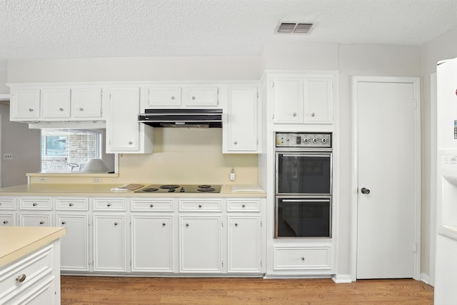 2910 Riata Ln, Houston, TX 77043 - kitchen with double wall oven, under cabinet range hood, electric cooktop, light countertops, and a textured ceiling