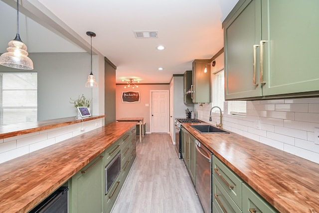 19923 Ricewood Way, Katy, TX 77449 - kitchen with wooden counters, green cabinetry, appliances with stainless steel finishes, light wood-style flooring, and decorative backsplash