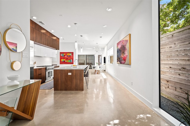 509 W Drew St, Houston, TX 77006 - kitchen featuring modern cabinets, stainless steel stove, concrete floors, a center island with sink, and backsplash