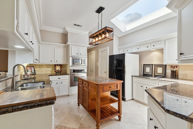 6606 Preston Trail Dr, Houston, TX 77069 - kitchen featuring stainless steel appliances, a skylight, tasteful backsplash, white cabinetry, and pendant lighting