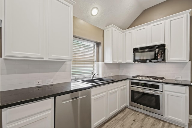 15919 Shadow Pass Trl, Tomball, TX 77377 - kitchen with appliances with stainless steel finishes, light wood-type flooring, dark countertops, lofted ceiling, and a textured ceiling