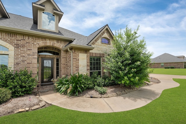 10527 Caddo Lake Dr, Needville, TX 77461 - view of front of home featuring brick siding, a front yard, roof with shingles, and stone siding