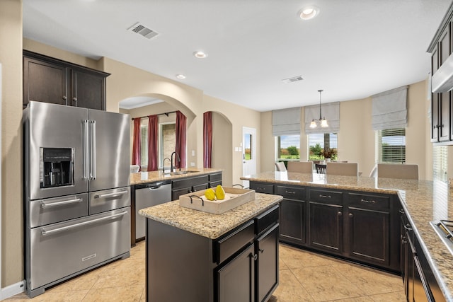 10527 Caddo Lake Dr, Needville, TX 77461 - kitchen featuring appliances with stainless steel finishes, a peninsula, arched walkways, a kitchen island, and light tile patterned floors