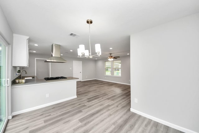 5634 Beldart St, Houston, TX 77033 - kitchen with island exhaust hood, white cabinetry, a chandelier, light wood-style flooring, and hanging light fixtures