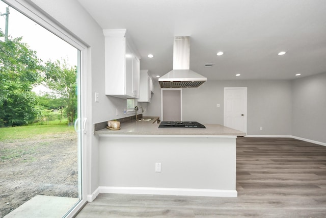 5634 Beldart St, Houston, TX 77033 - kitchen featuring island range hood, white cabinetry, stainless steel gas stovetop, light wood finished floors, and recessed lighting