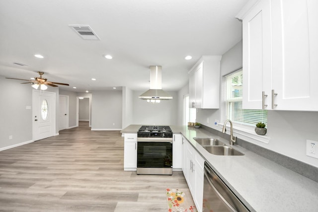 5634 Beldart St, Houston, TX 77033 - kitchen with stainless steel appliances, island exhaust hood, plenty of natural light, white cabinets, and recessed lighting