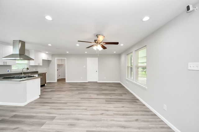 5634 Beldart St, Houston, TX 77033 - kitchen with wall chimney range hood, recessed lighting, a ceiling fan, white cabinets, and light wood-type flooring