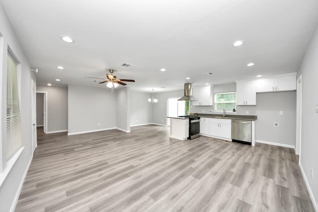 5634 Beldart St, Houston, TX 77033 - kitchen with stainless steel dishwasher, range with gas stovetop, wall chimney exhaust hood, open floor plan, and recessed lighting