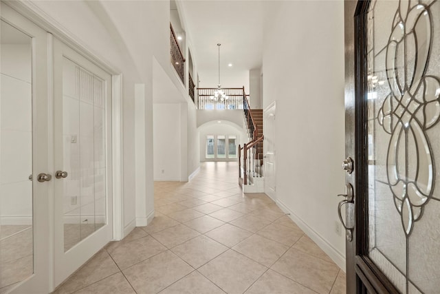 4403 Lodge Vine Ct, Sugar Land, TX 77479 - foyer featuring arched walkways, light tile patterned flooring, a chandelier, a high ceiling, and french doors