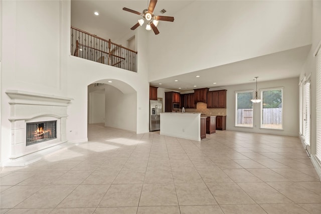 4403 Lodge Vine Ct, Sugar Land, TX 77479 - unfurnished living room with ceiling fan, a glass covered fireplace, light tile patterned flooring, arched walkways, and recessed lighting