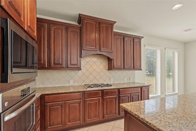 4403 Lodge Vine Ct, Sugar Land, TX 77479 - kitchen with appliances with stainless steel finishes, light stone countertops, decorative backsplash, light tile patterned flooring, and recessed lighting