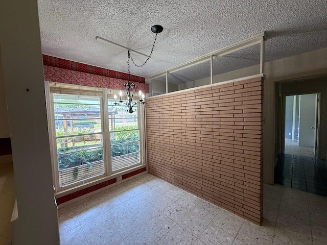 427 22nd Ave N, Texas City, TX 77590 - unfurnished dining area with a chandelier, tile patterned floors, a textured ceiling, and brick wall