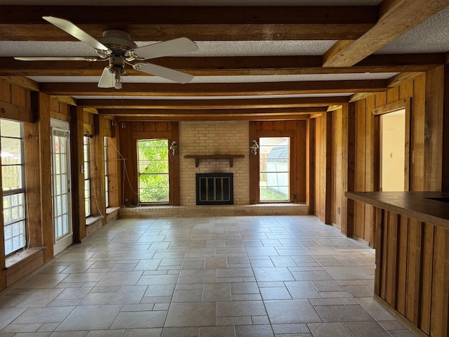 427 22nd Ave N, Texas City, TX 77590 - unfurnished living room featuring wooden walls, beamed ceiling, ceiling fan, a fireplace, and stone finish flooring