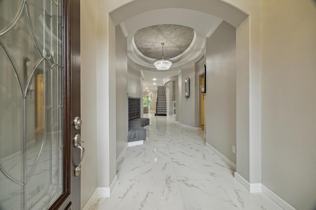 17310 Venado Dr, Cypress, TX 77433 - corridor featuring arched walkways, light marble finish floors, crown molding, a tray ceiling, and stairs