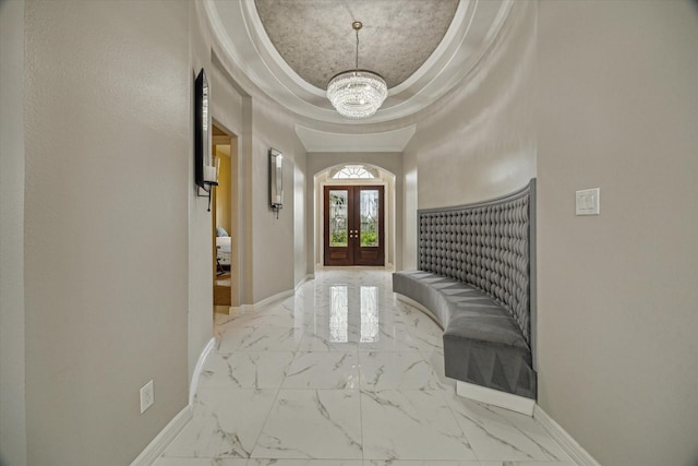 17310 Venado Dr, Cypress, TX 77433 - foyer entrance with marble look tile flooring, a raised ceiling, a chandelier, french doors, and crown molding