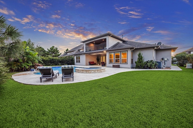 17310 Venado Dr, Cypress, TX 77433 - back of house at dusk with stucco siding, a balcony, a lawn, a patio area, and a pool with connected hot tub